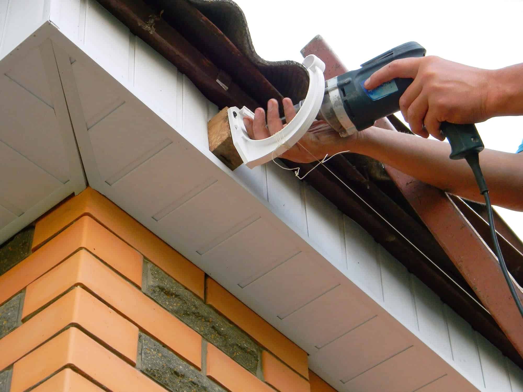Contractor securing a gutter bracket on a New Orleans roofline