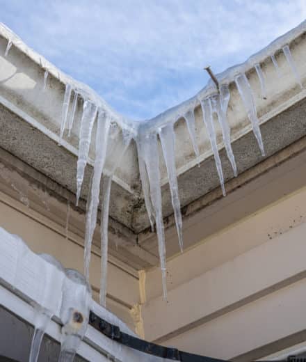 frozen gutters with long icicles hanging from ice dams - Big Easy Gutter