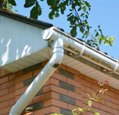 Close up on white plastic rain gutter. House roof guttering repair.