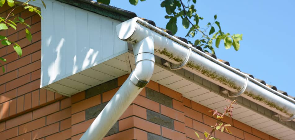 Close up on white plastic rain gutter. House roof guttering repair.